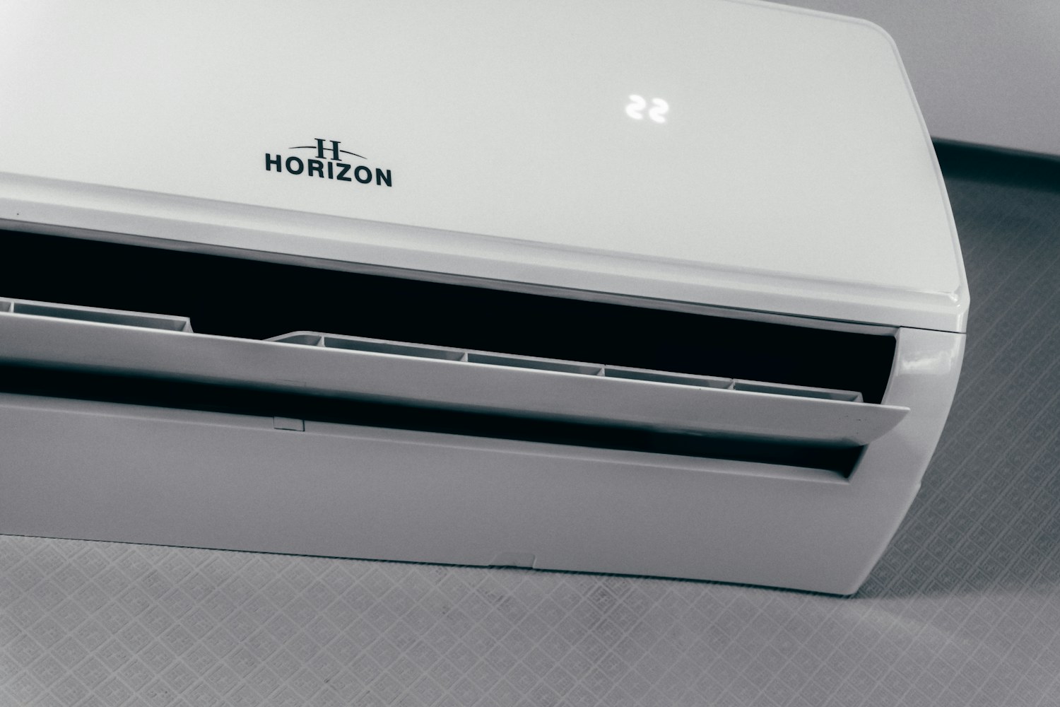 A white indoor wall-mounted air-conditioning unit with its supply louver open