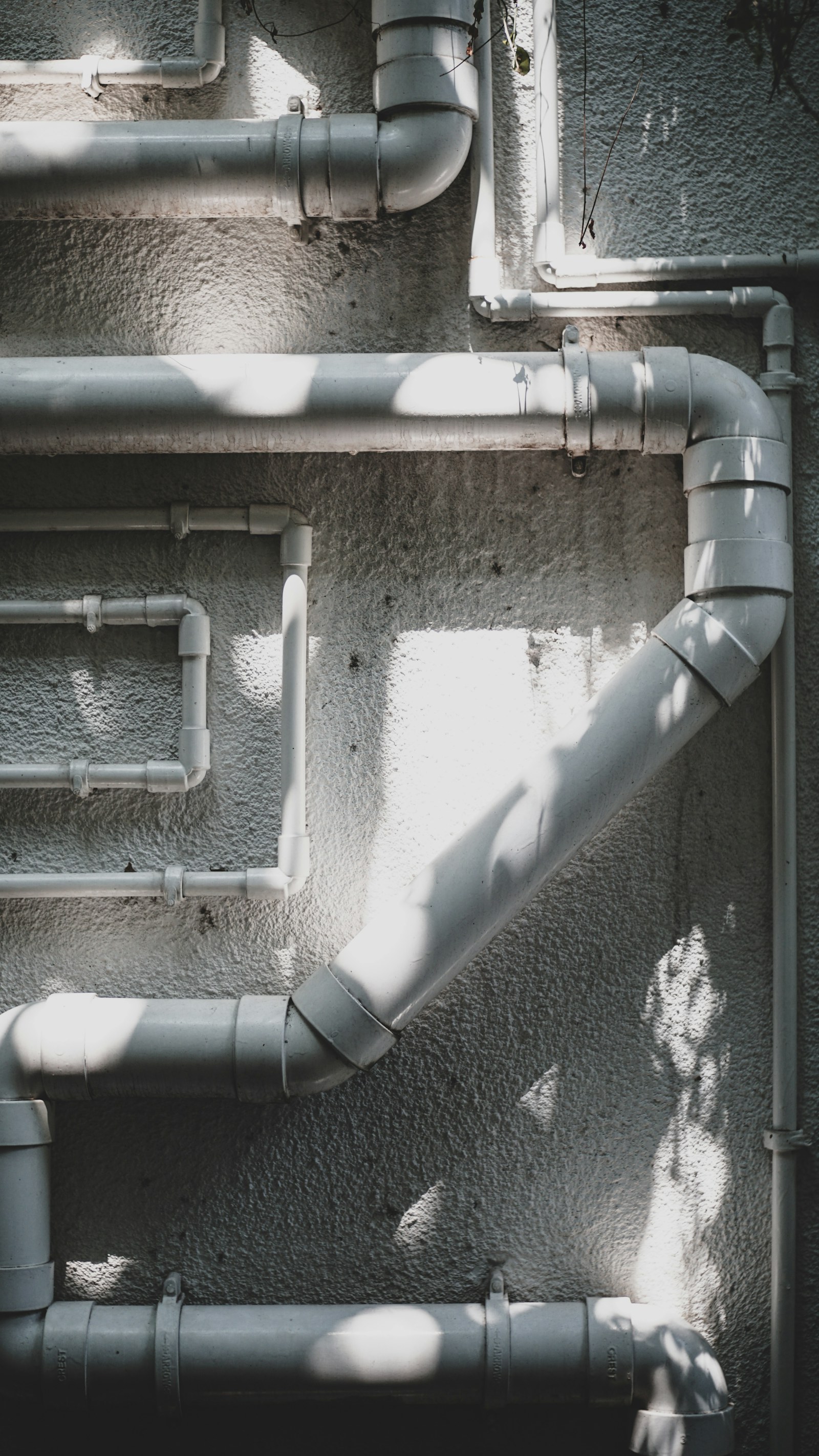 Exposed pipes and fittings mounted on a textured wall