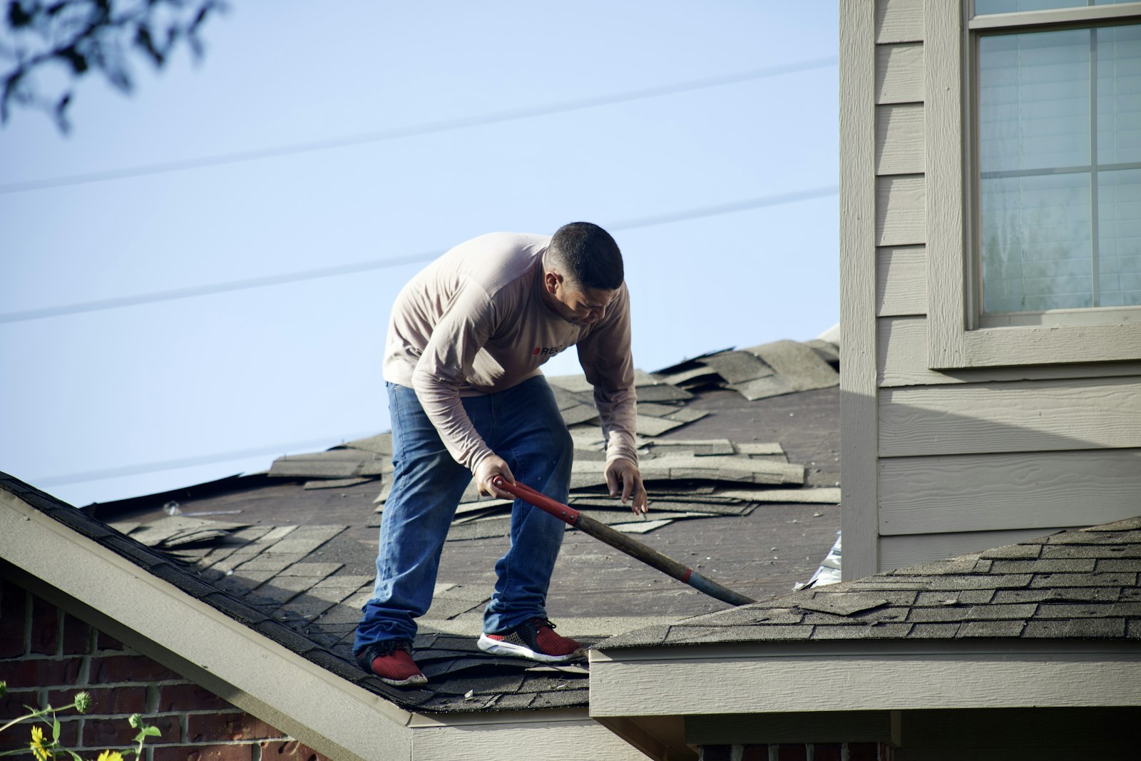 An installer removing the existing roof covering during a complete roof replacement