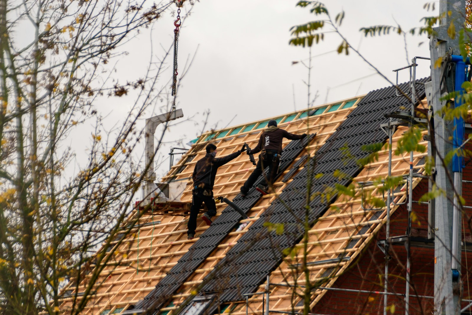 Installers placing roof covering across a new residential roof